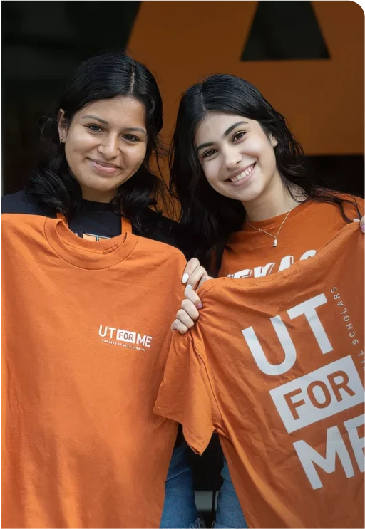Two women holding up "UT for me" shirts