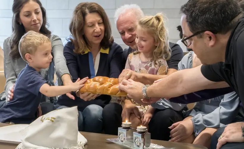 Woman holding out a large piece of bread, letting two small children touch it