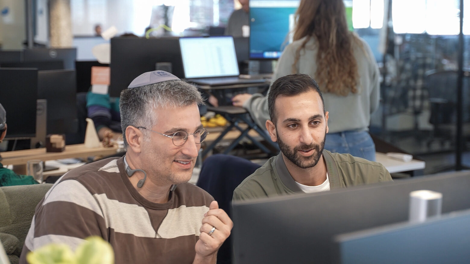 Two Eleos workers review work at a computer desk.